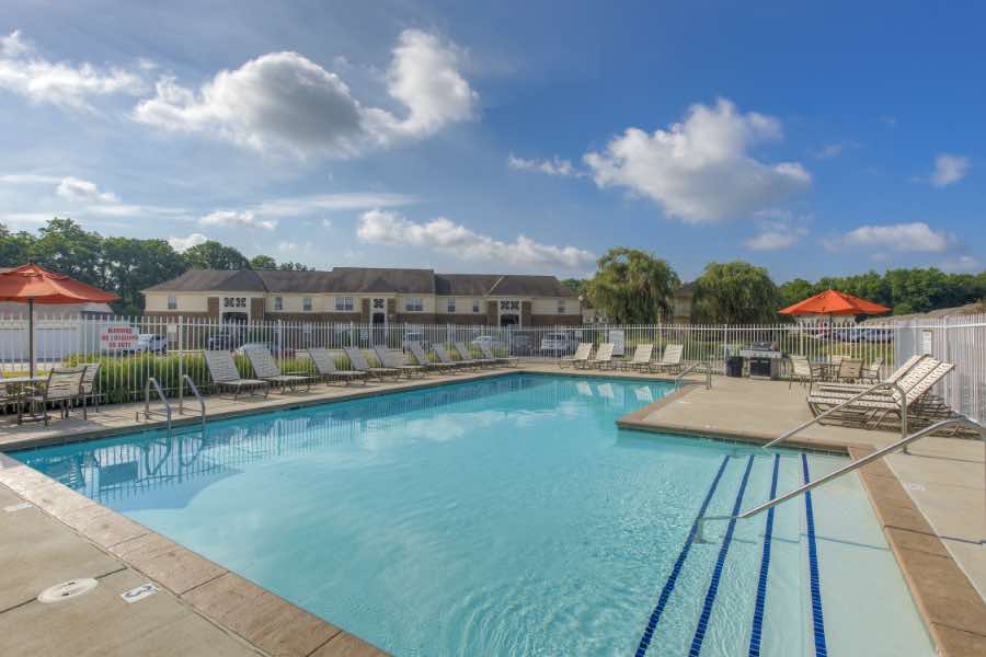 Apartment swimming pool with lounge chairs and tables with umbrellas